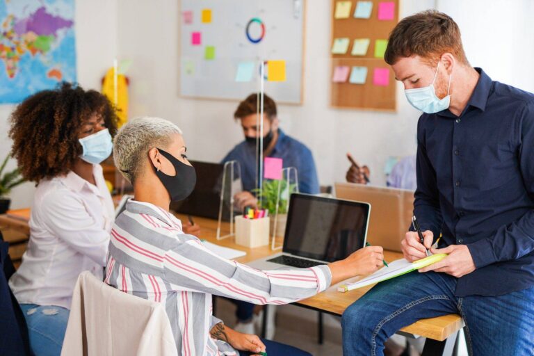 Neue Corona-Regeln im Job 4 multiracial people in coworking office with safety measures for coronavirus