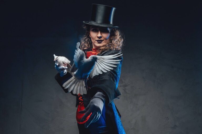 Gehalt: Wie viel verdient ein Zauberer? 2 serious female magician with white pigeons and top hat in dark background