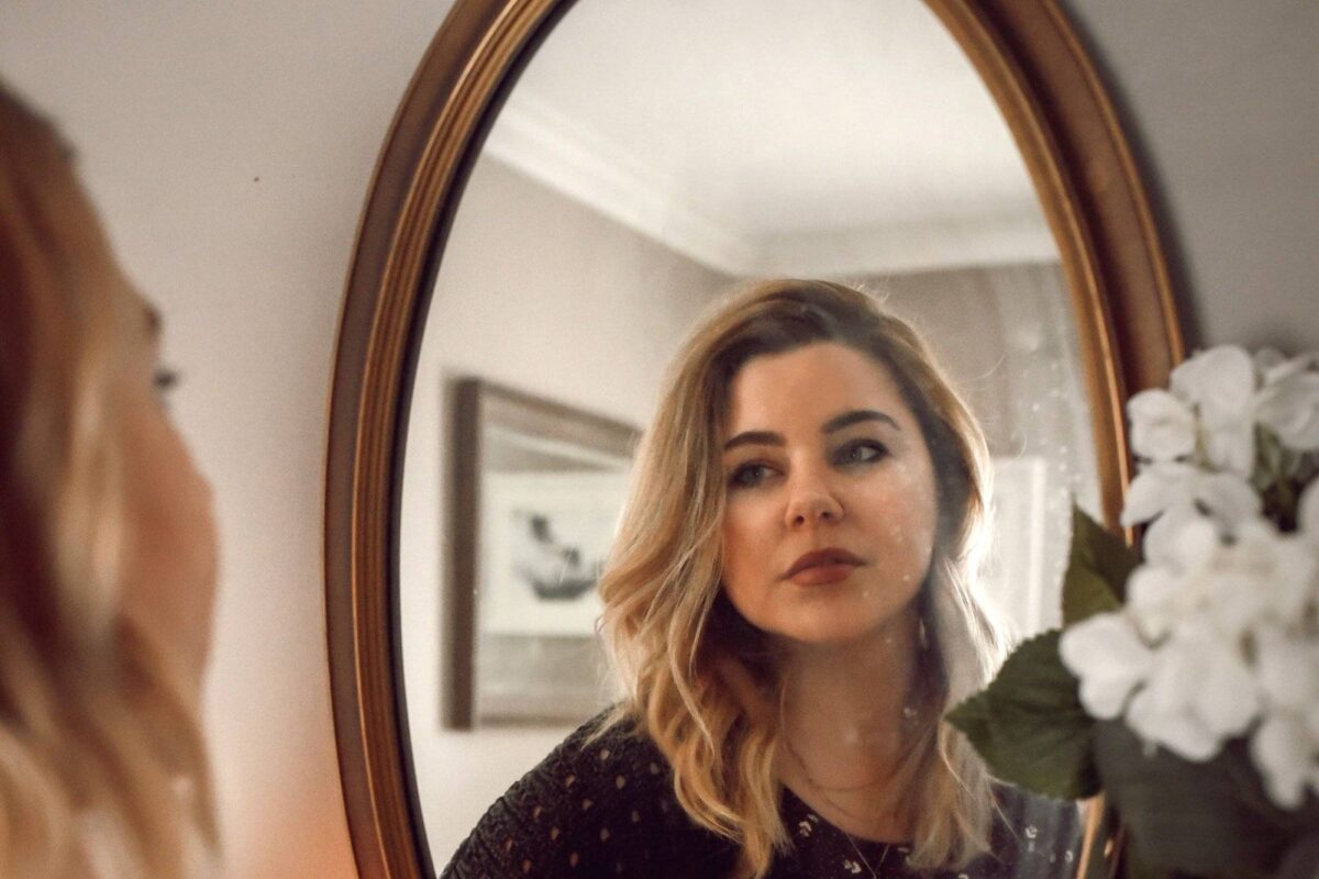 Eine Frau blickt mit skeptischem Gesichtsausdruck in den Spiegel