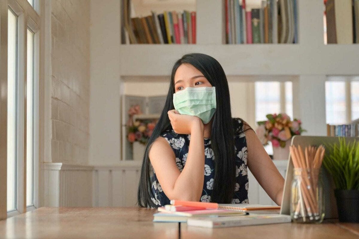 Female students wear a mask and look out the window,coronary virus or Covid-19 concepts.